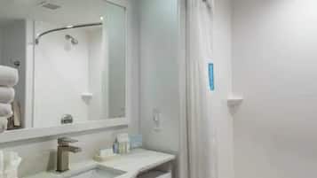 Un baño con lavamanos, espejo y ducha.