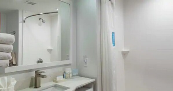 A bathroom with a sink, mirror, and shower. - Hampton Inn Brownwood (Brownwood)