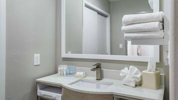 A bathroom with a sink, mirror, towel rack, and toiletries.