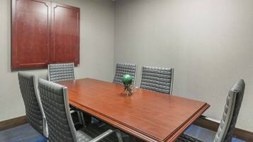 A conference room with a wooden table, six upholstered chairs, and a large wooden cabinet.