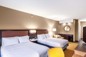 Two single beds with white linens, a bedside table, and a desk with a telephone.