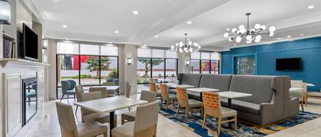 A modern dining area with tables and chairs, a sofa, and a TV.