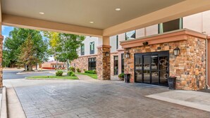 A hotel entrance with a stone facade, large windows, and a covered walkway.