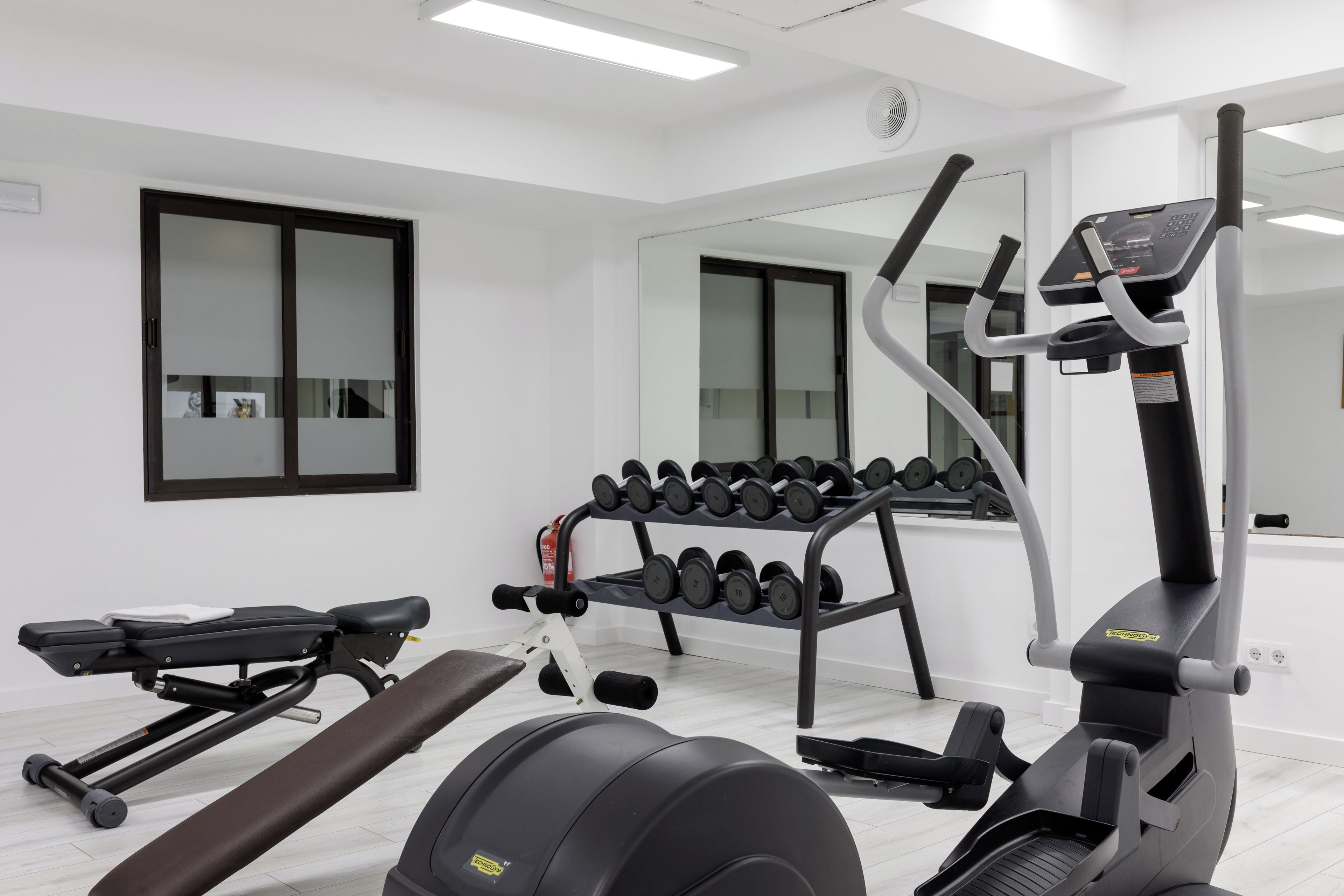 Una palestra con attrezzature per esercizi, tra cui tapis roulant, manubri e una panca.