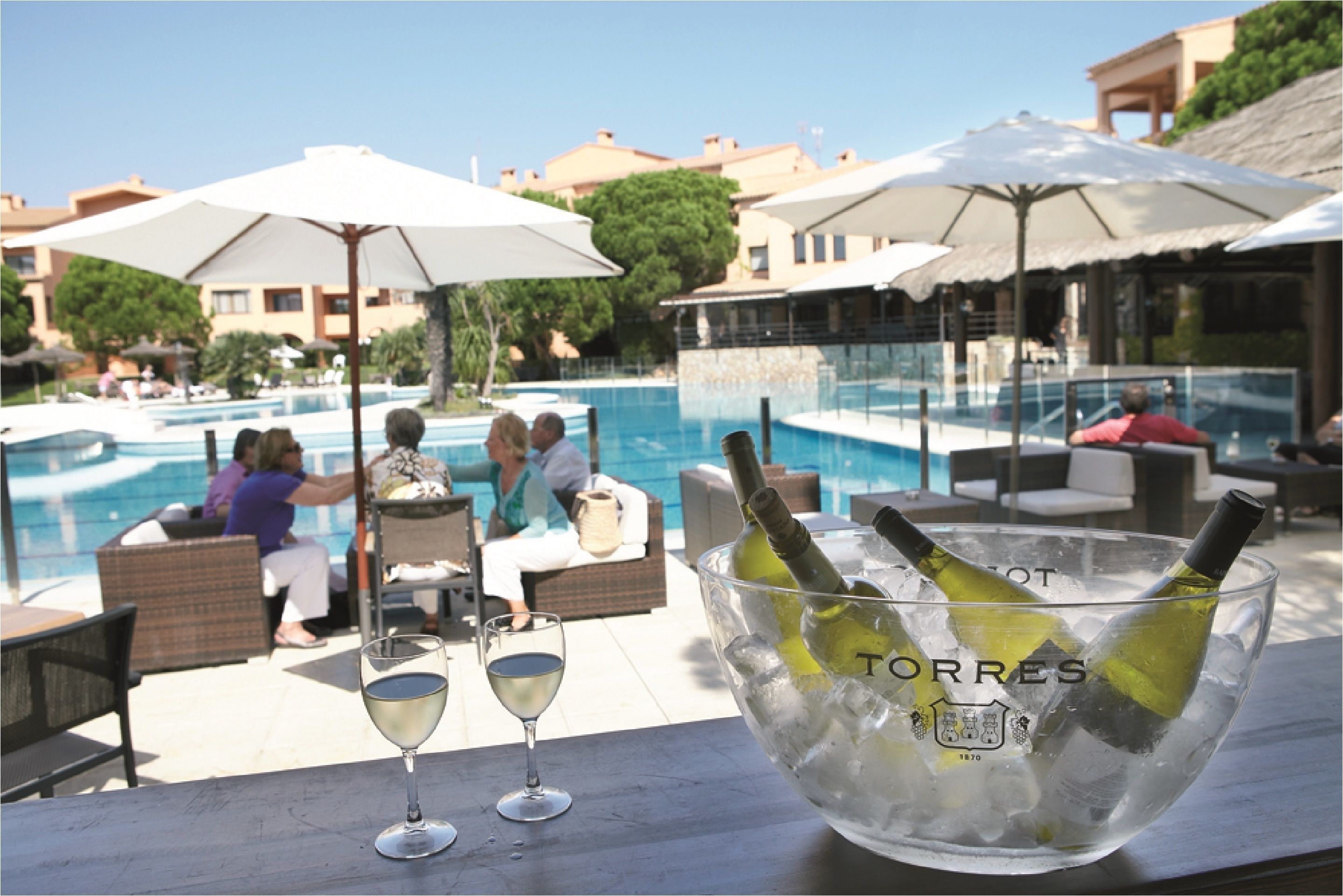 Ein Poolbereich mit Liegestühlen, Sonnenschirmen und einer Glasbowl mit Flaschen und Eis.