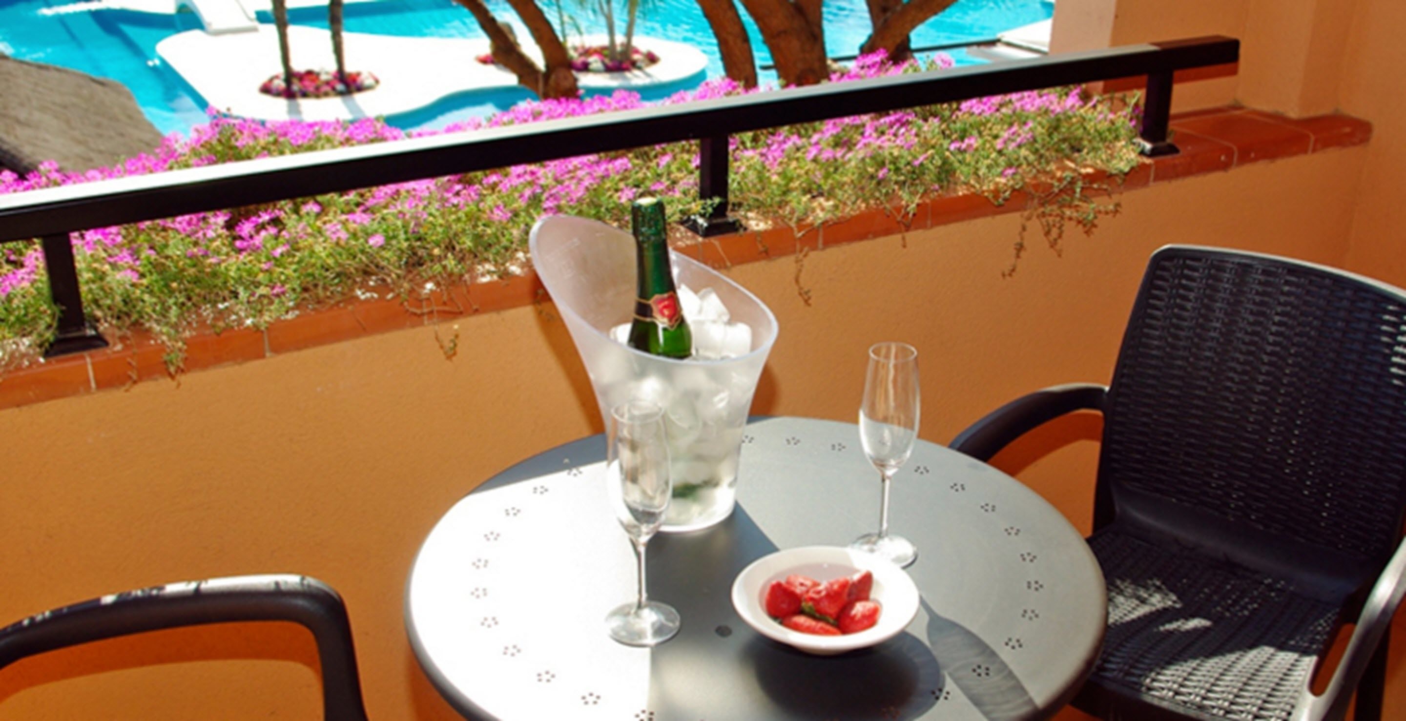Une table avec une bouteille de champagne, deux verres et un bol de fraises.