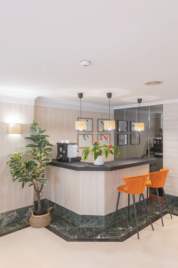 A modern kitchen with a built-in island, two pendant lights, a coffee machine, and a potted plant. - Hotel Soho Boutique Los Naranjos (Málaga)