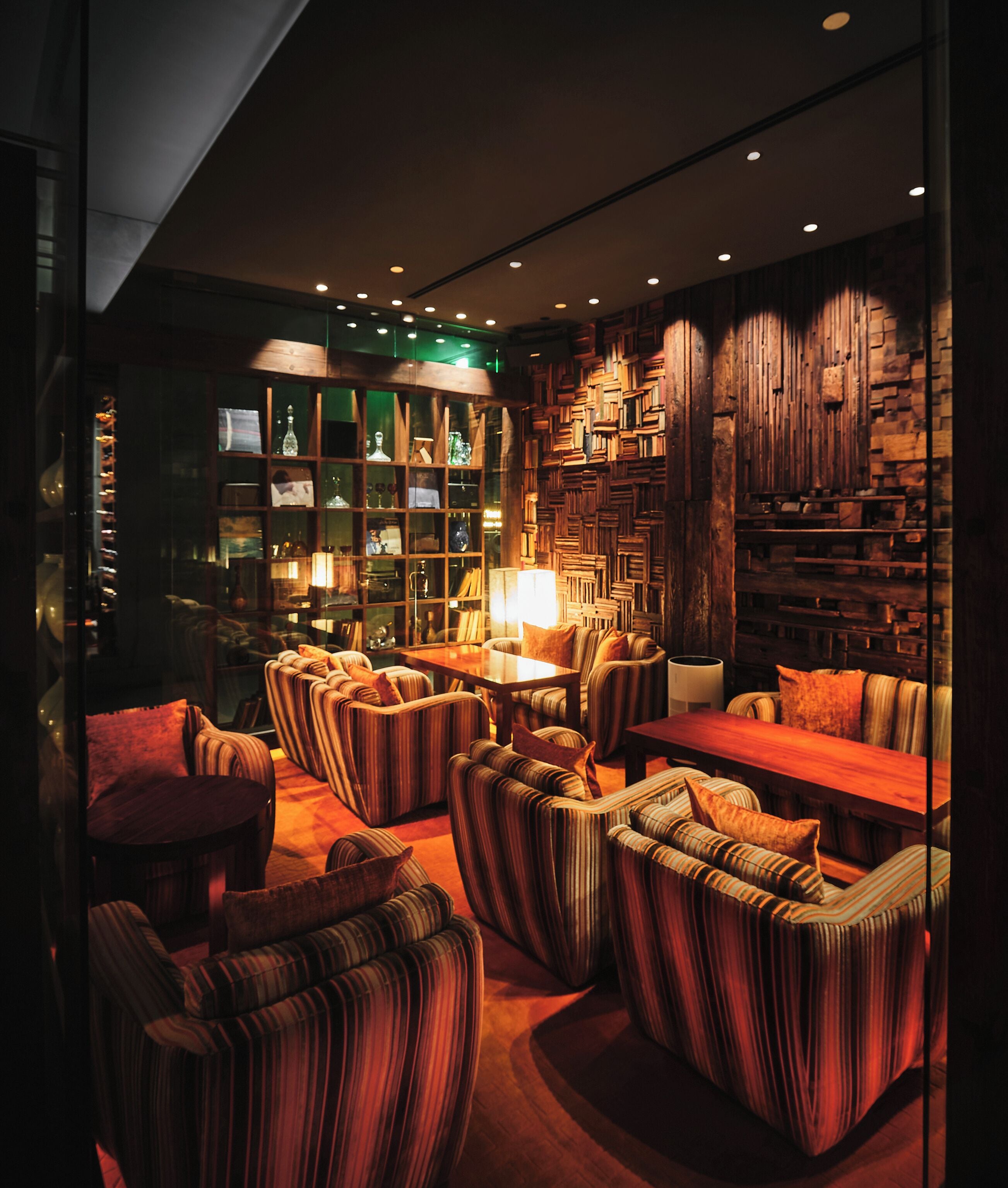 A cozy, dimly lit lounge area with striped upholstered sofas and a wooden coffee table.
