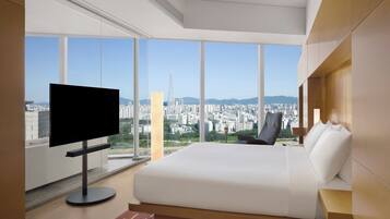 Quarto de hotel moderno com uma cama grande, televisão de tela plana e vista para a cidade.