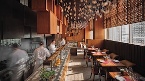 A modern restaurant interior with wooden paneling, hanging light fixtures, and a long dining counter. - Park Hyatt Seoul (Seoul)