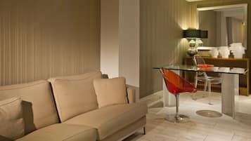 A modern living room with a beige sofa, a glass coffee table, and a clear chair.