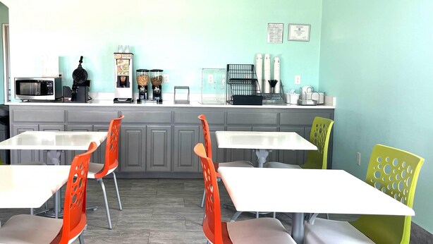 A dining area with tables and chairs, a microwave, coffee machine, and a food dispenser. - Quality Inn Montgomery - Lake Conroe (Montgomery)