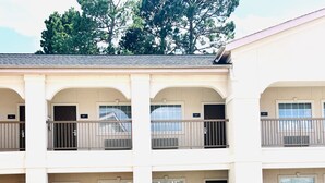 A multi-story motel with a swimming pool, outdoor seating, and a fenced balcony area. - Quality Inn Montgomery - Lake Conroe (Montgomery)