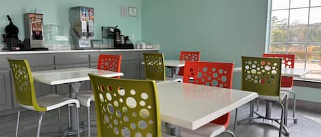 A dining area with a light green wall, a window with a view, and a counter with kitchen appliances.