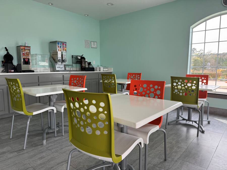 A dining area with a light green wall, a window with a view, and a counter with kitchen appliances.