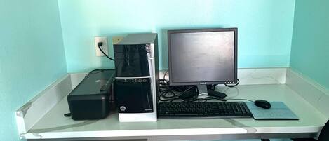 A computer desk with an HP Pavilion desktop computer, a Dell monitor, a keyboard, and a mouse.