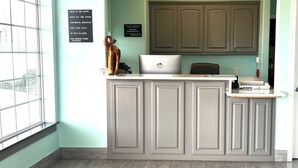 A reception desk with a laptop, a bronze sculpture, and a sign listing amenities like continental breakfast and free local calls. - Quality Inn Montgomery - Lake Conroe (Montgomery)