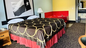 A hotel room with a large bed, a red headboard, a red sofa, a small table, a lamp, and a framed picture on the wall. - Quality Inn Montgomery - Lake Conroe (Montgomery)