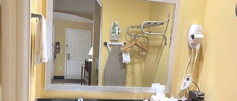 A bathroom with a large mirror, a sink, and a hairdryer.