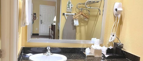 Un baño con lavamanos, espejo y perchero para toallas.