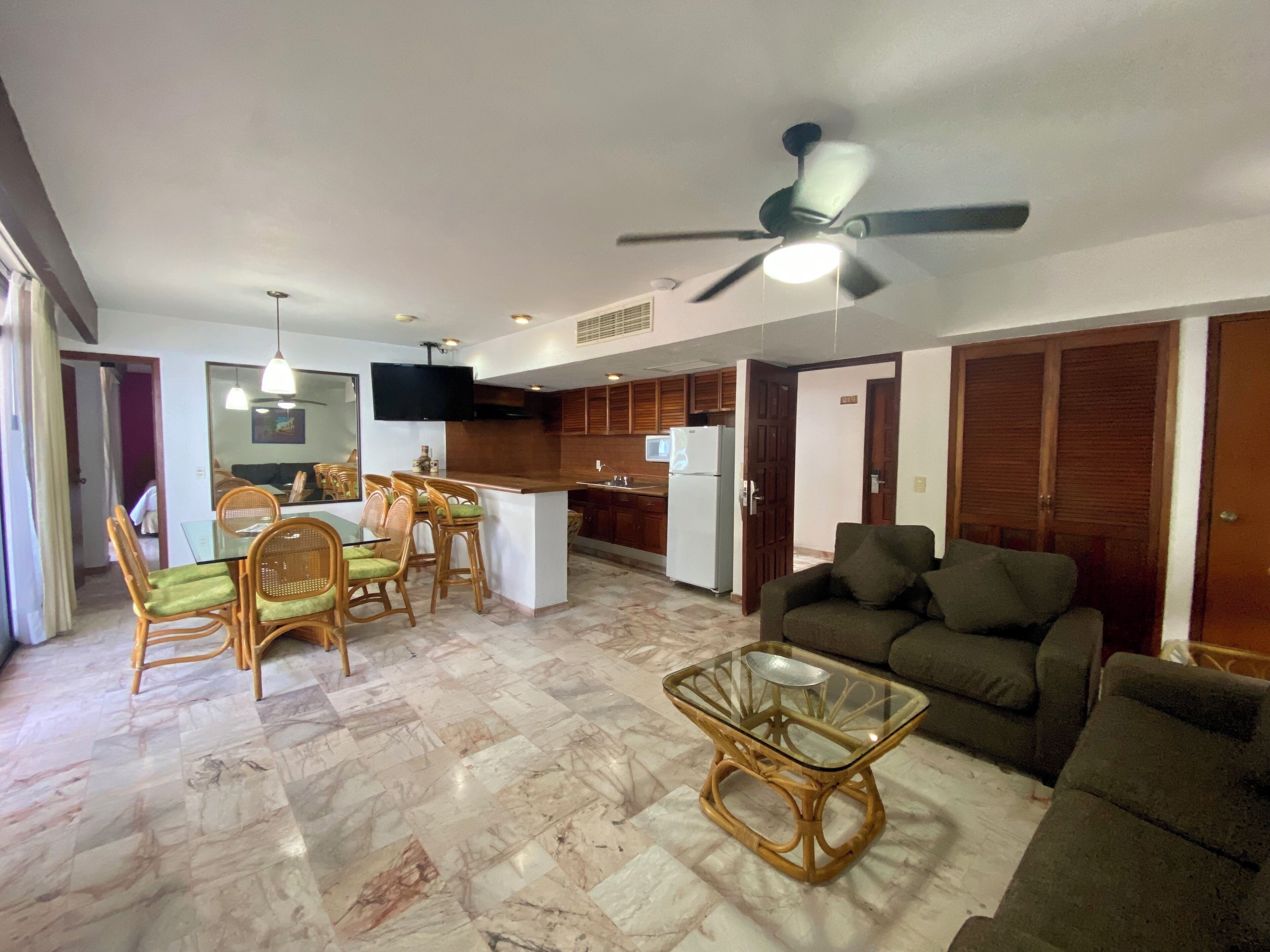 A spacious living area with a glass coffee table, a sofa, and a dining set with chairs.