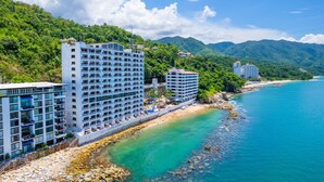 A coastal hotel with multiple floors, a beachside location, and a view of the sea and mountains. - Costa Sur All Inclusive Resort (Puerto Vallarta)