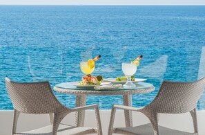 A table with two chairs and a glass of drink with a lemon slice on a balcony overlooking the sea. - Costa Sur All Inclusive Resort (Puerto Vallarta)