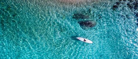 Una piscina azul cristalina con una persona en una tabla de paddleboard.