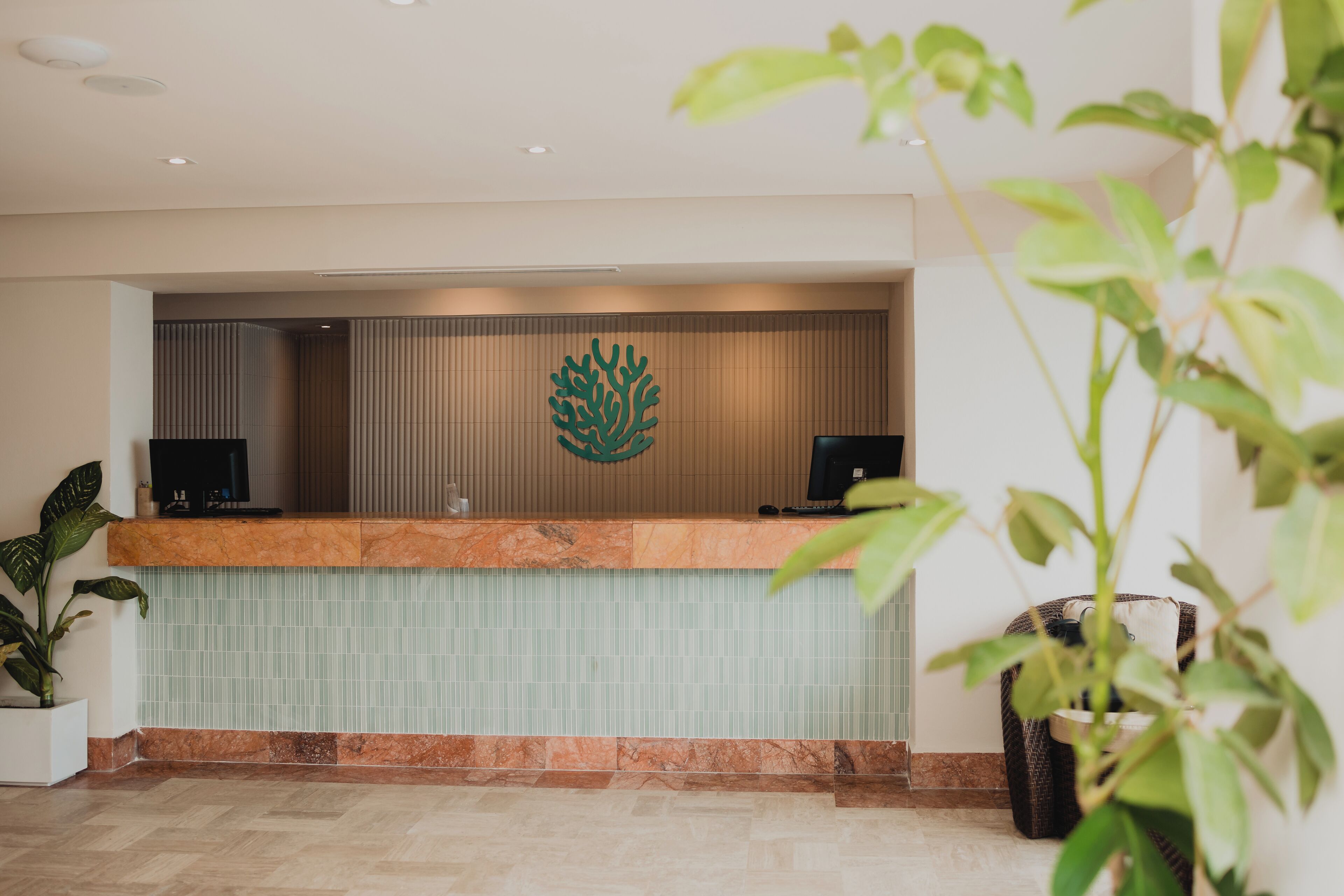 A reception area with a marble counter, two monitors, and a decorative wall piece.