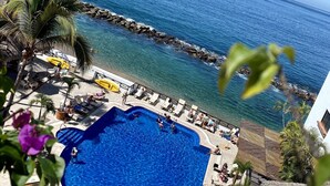 A resort with a large pool, lounge chairs, and a view of the ocean.