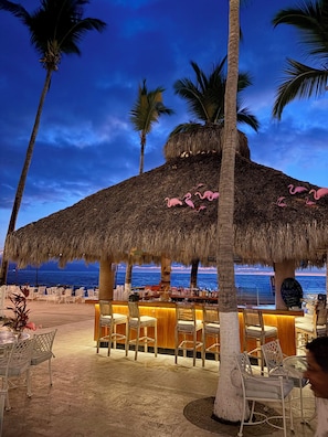 A beachside bar with thatched roof, white wicker furniture, and a view of the ocean. - Costa Sur All Inclusive Resort (Puerto Vallarta)