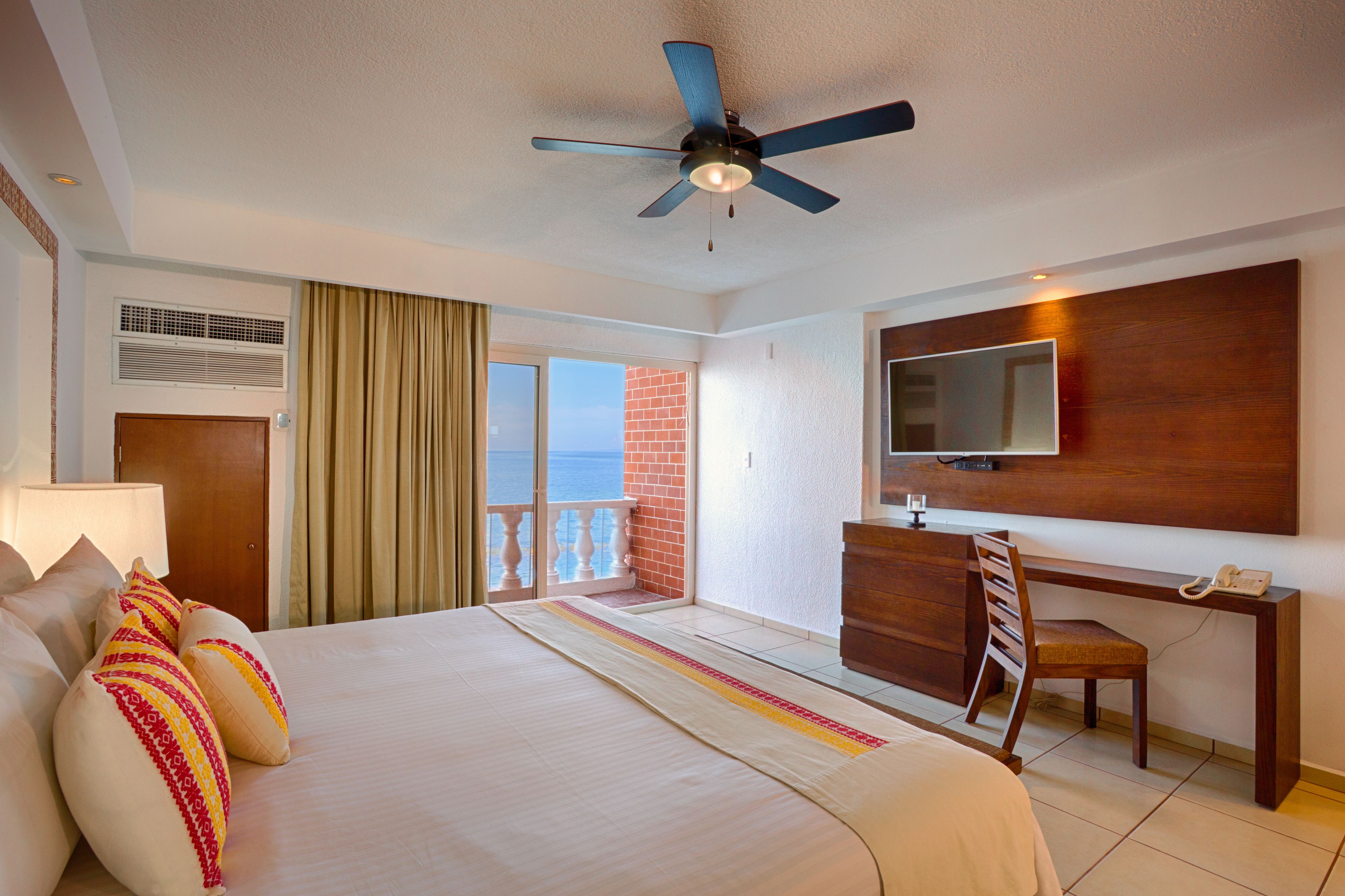 Une chambre d’hôtel avec un lit, un bureau et une chaise, une télévision et un balcon avec vue.
