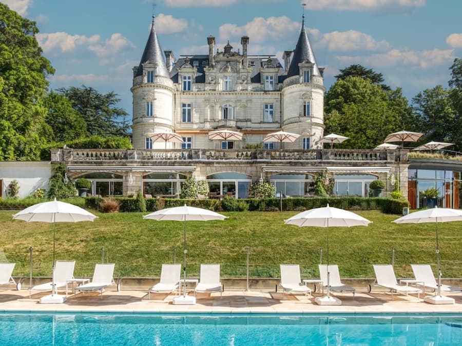Un grand bâtiment historique doté d’une piscine, d’un espace extérieur aménagé et de parasols.