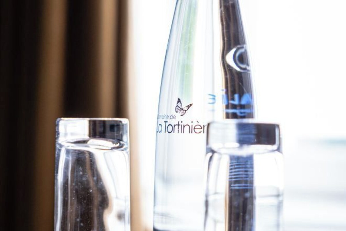 Una botella de vidrio transparente con un logotipo de mariposa y el texto 'la fortiniere'.