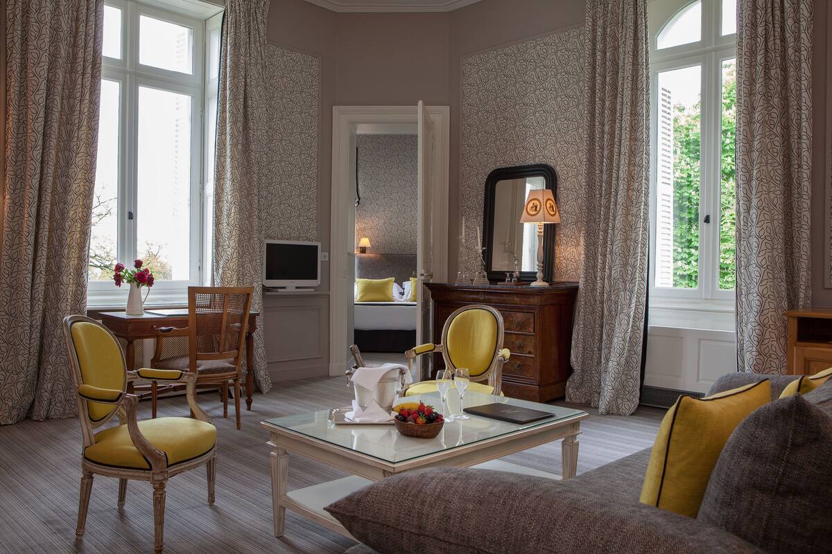 A well-lit room with a dining table, chairs, a sofa, and a television.