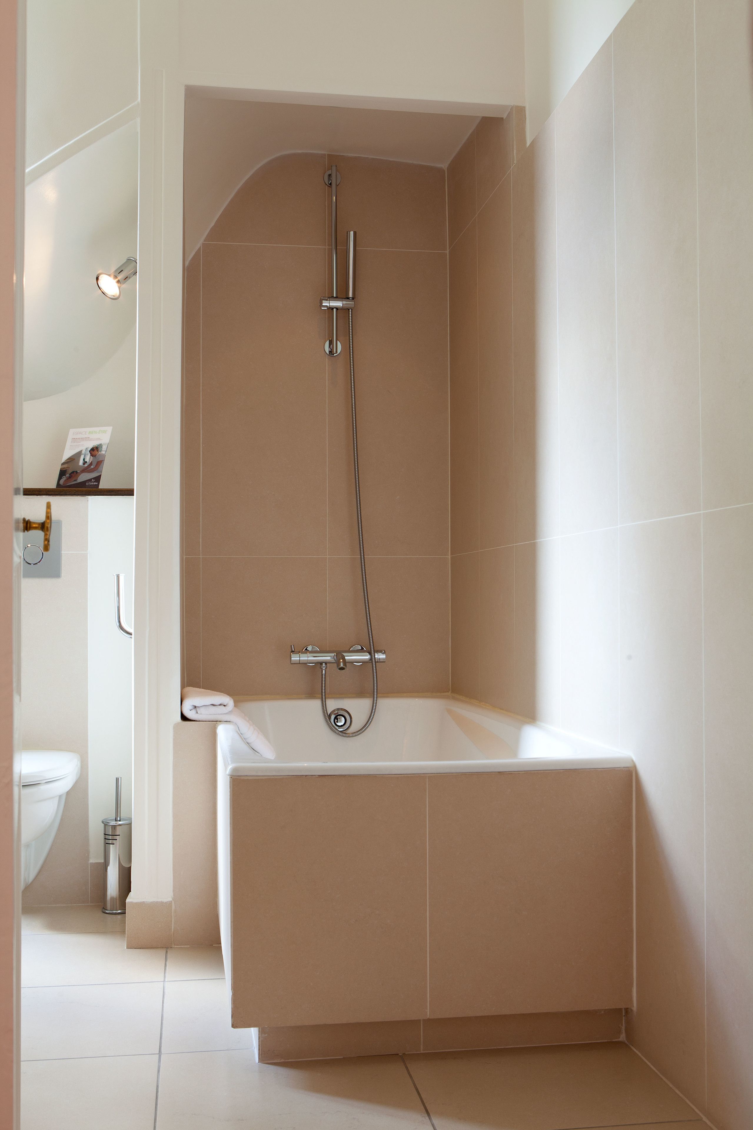 A modern bathroom with a bathtub, shower, and toilet.