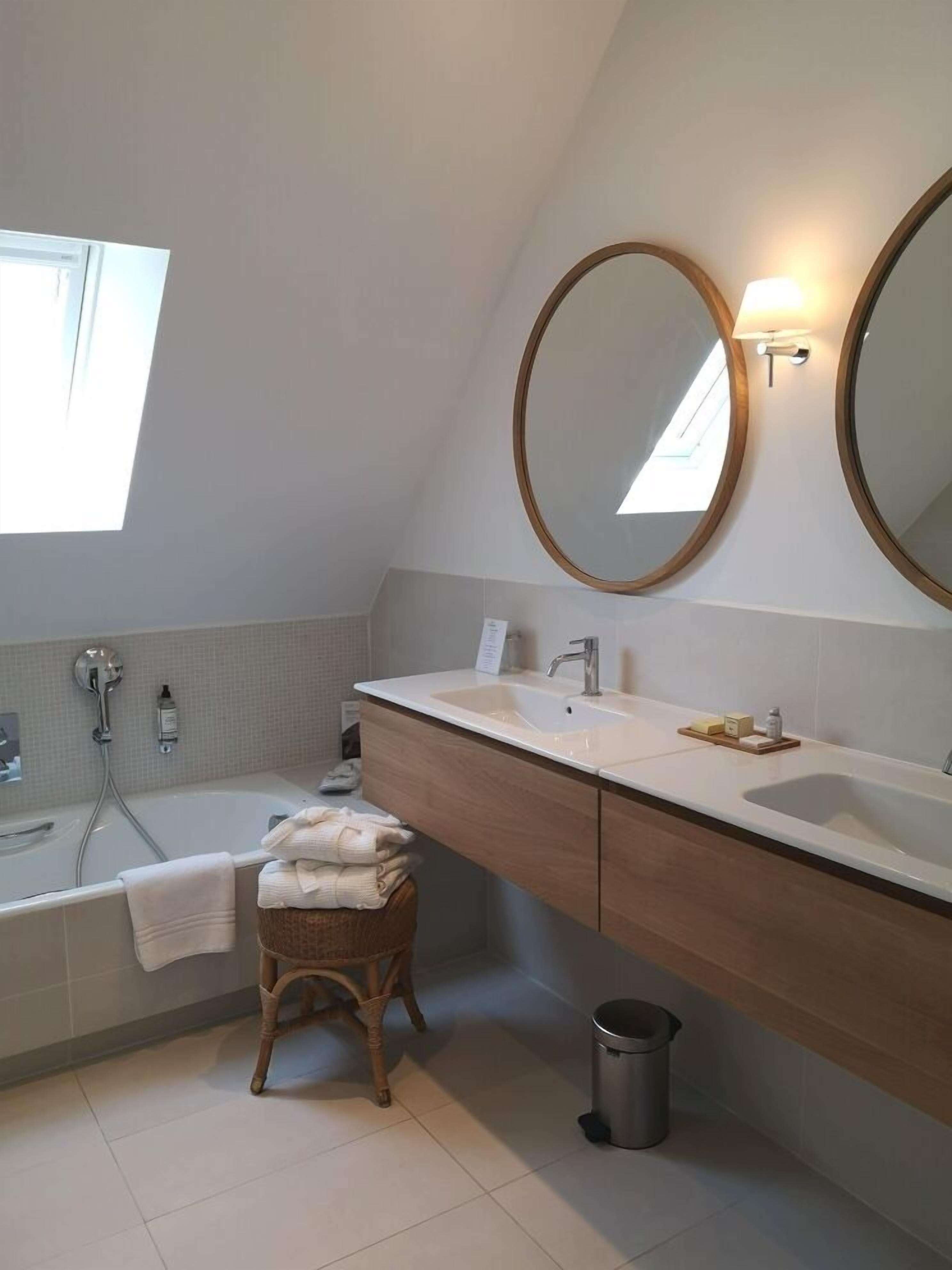 Un baño moderno con una bañera independiente, un tocador con un espejo grande y un pequeño taburete.