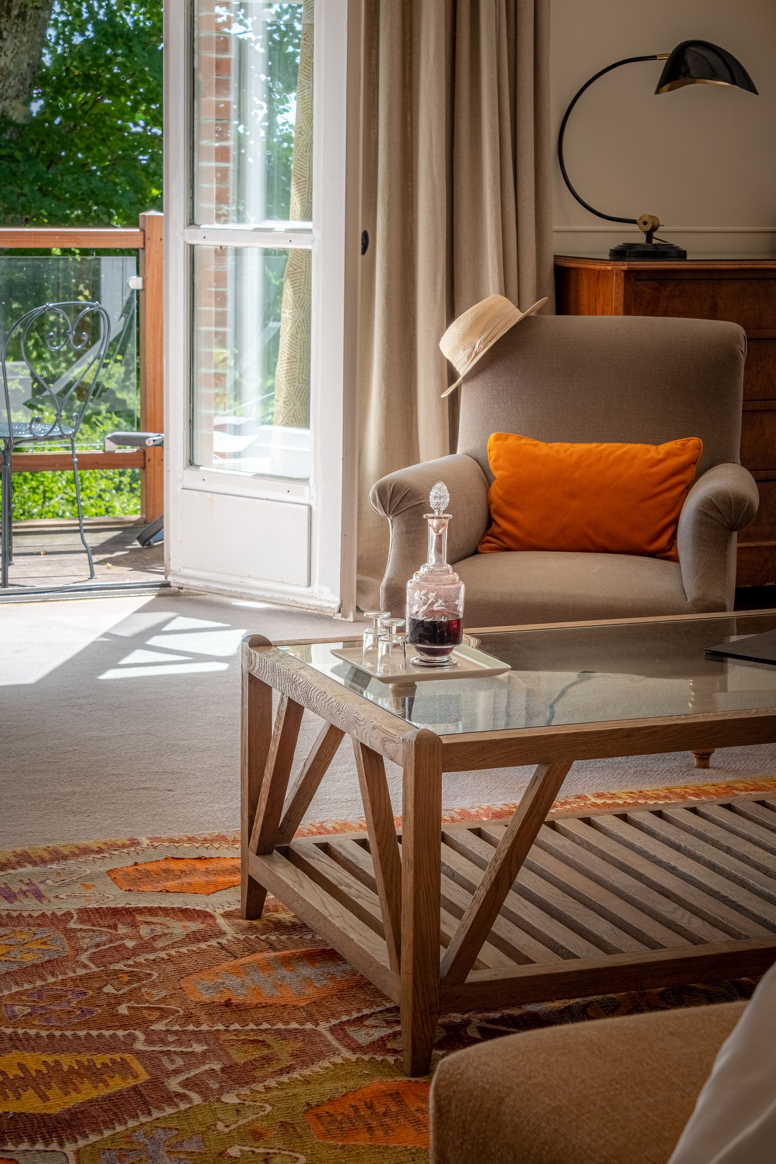 A cozy living room with a comfortable armchair, a glass coffee table, and a patterned rug.