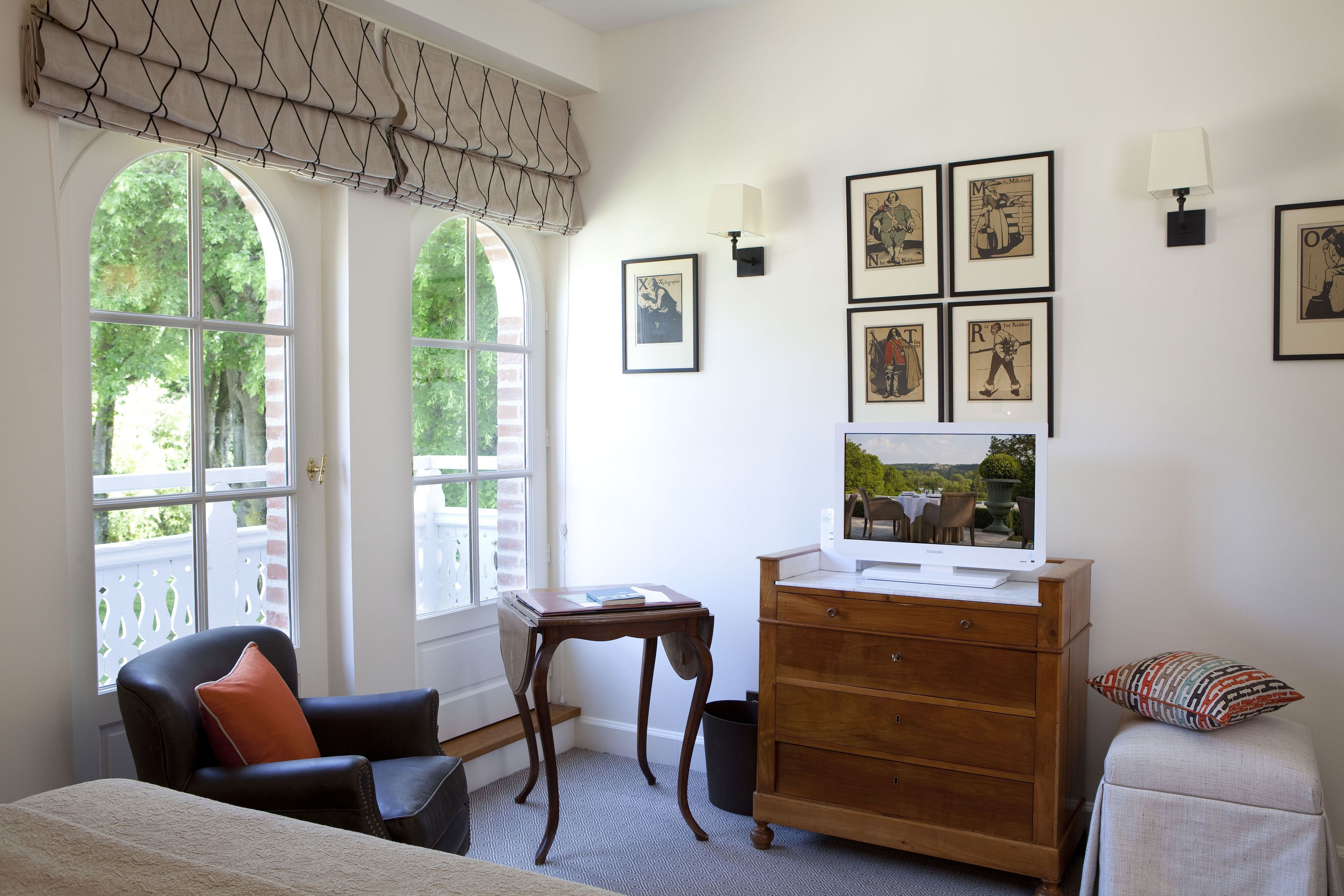 Een kamer met een bed, bureau, dressoir en een televisie.