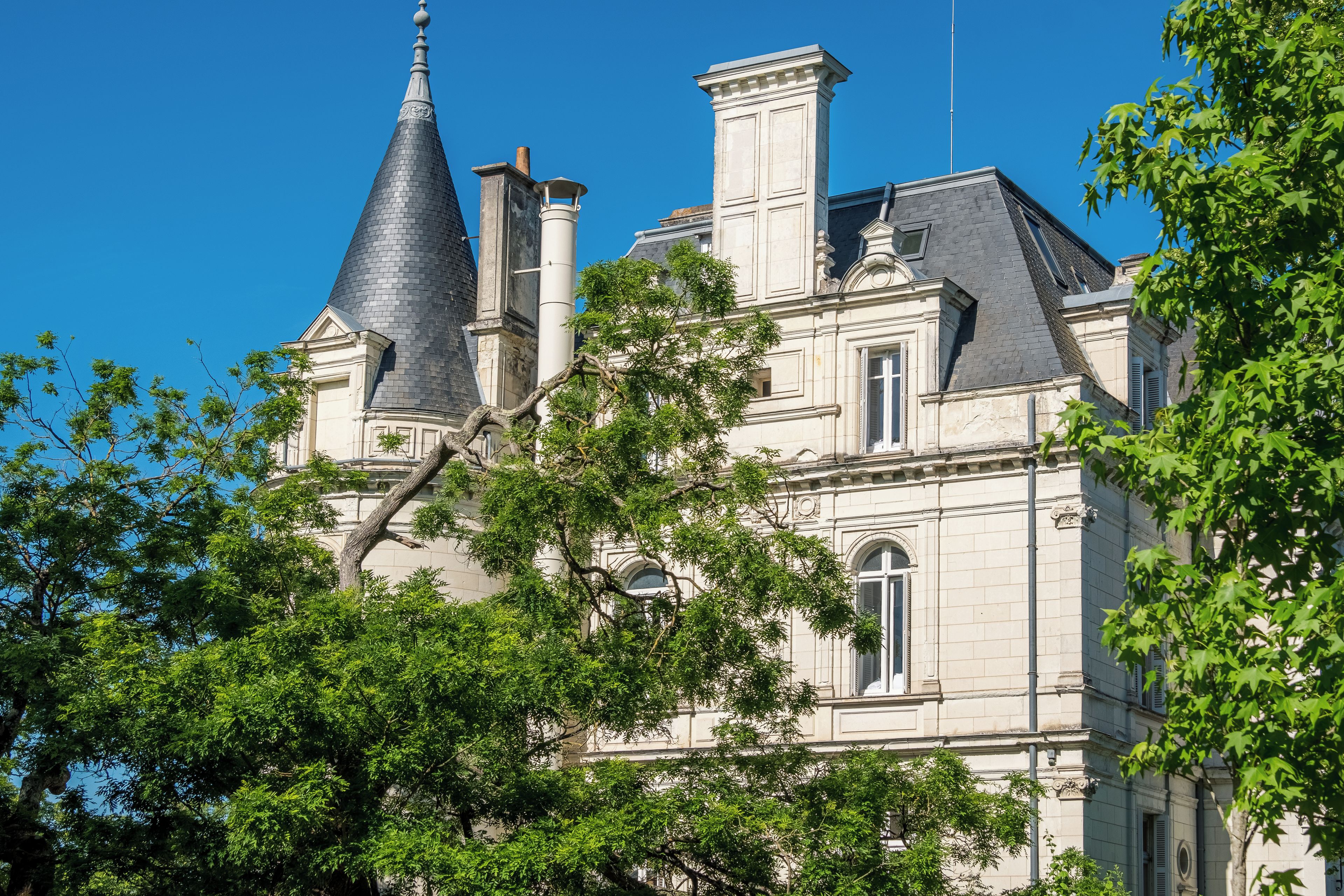 A historic building with a prominent tower and multiple chimneys.