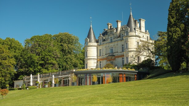Un grand bâtiment historique doté de nombreuses tours et d’une structure moderne en verre.