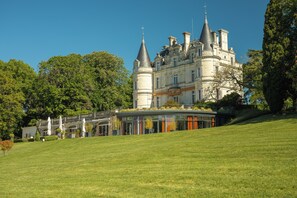 Un grand bâtiment historique doté de nombreuses tours et d’une structure moderne en verre.