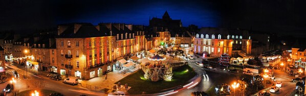 Una plaza histórica con edificios iluminados y una fuente en el centro.