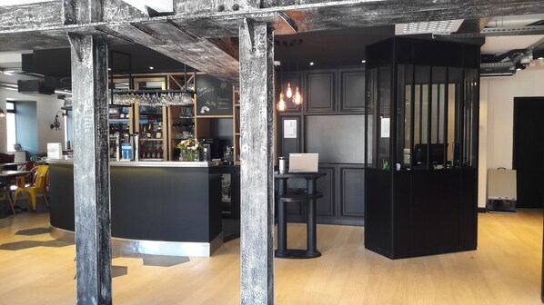 Un bar moderno con mostrador, taburetes y una laptop.