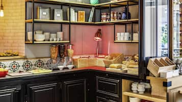 A kitchen with black cabinets, wooden shelves, and various food items.