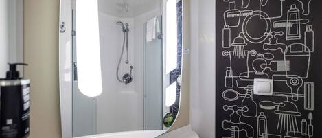 A bathroom with a large mirror, a shower, and a wall with bathroom-related icons.