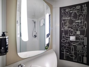 Ein Badezimmer mit einem großen Spiegel, einer Dusche und einer Wand mit Badezimmer-Symbolen.