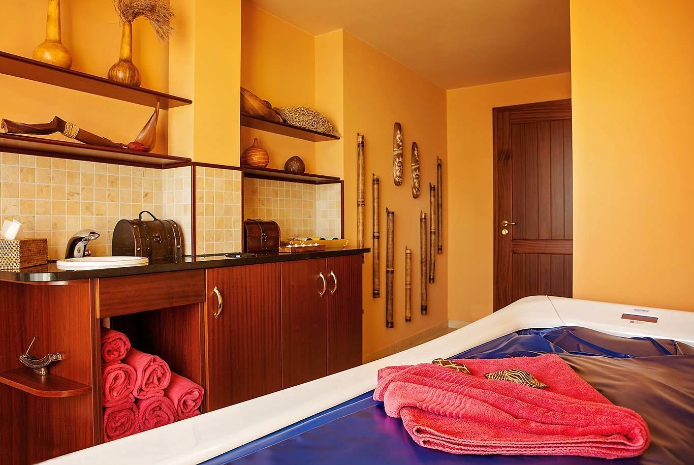 A hotel room with a wooden vanity, a bed with blue bedding, and a wall-mounted ski rack.