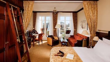A hotel room with a bed, a desk, a chair, a sofa, and a balcony with curtains.