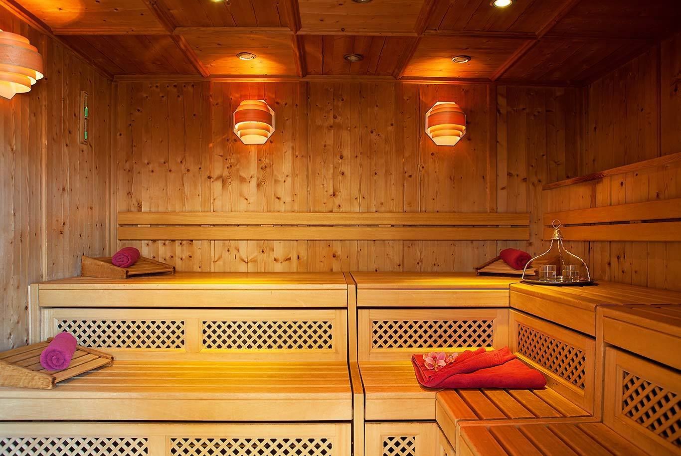 A wooden sauna with benches and a bench seat, equipped with a bench seat cover and a tray with glasses.